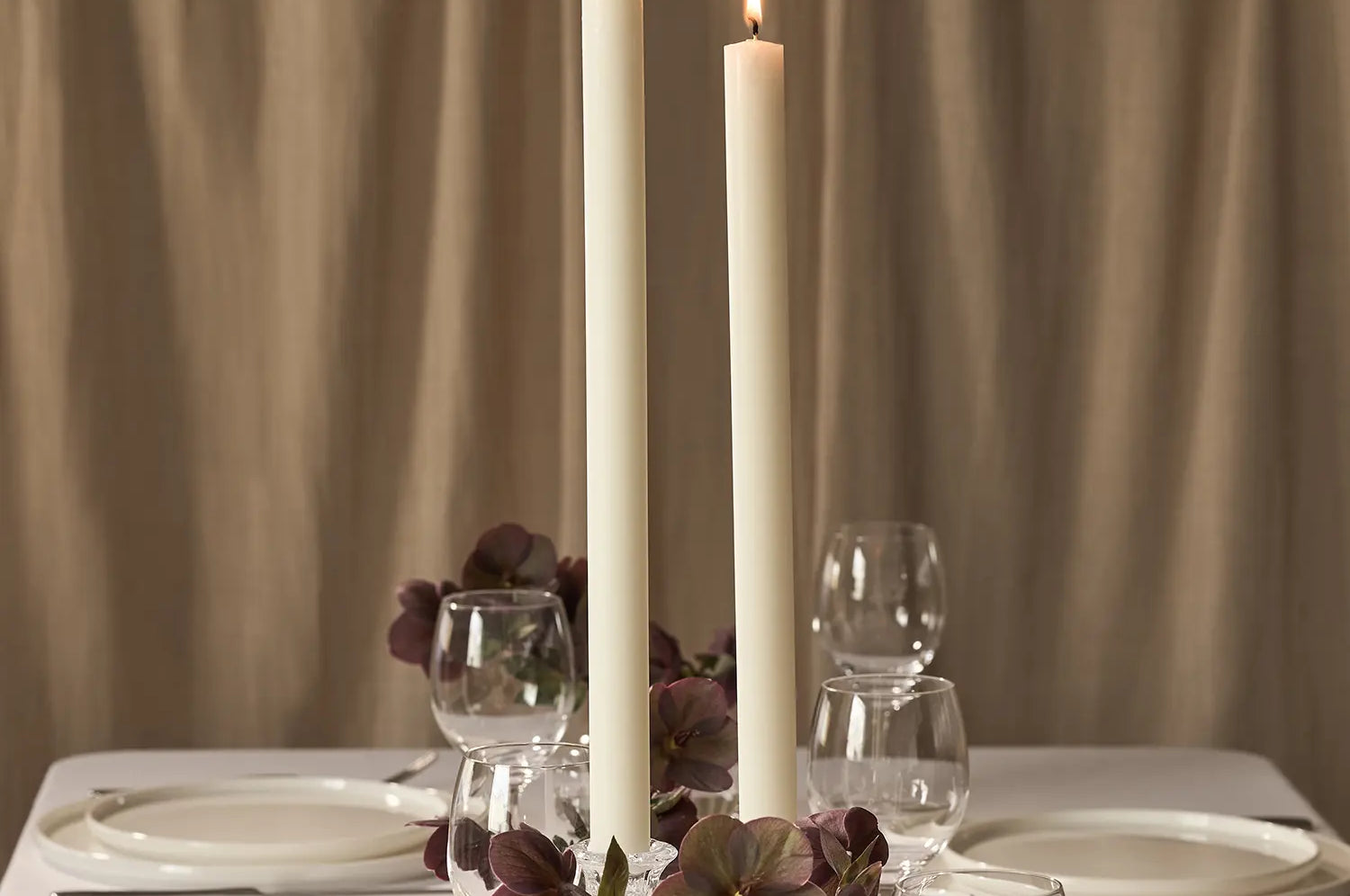 Two lit dining candles on a dining table.