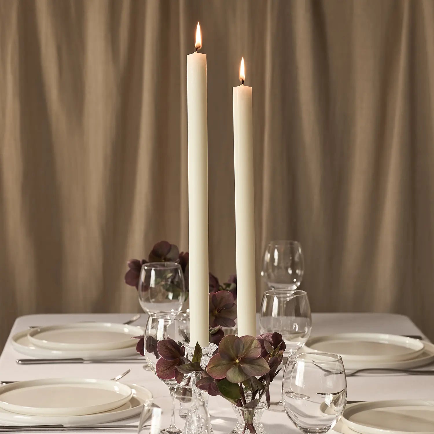 Two lit dining candles on a dining table.