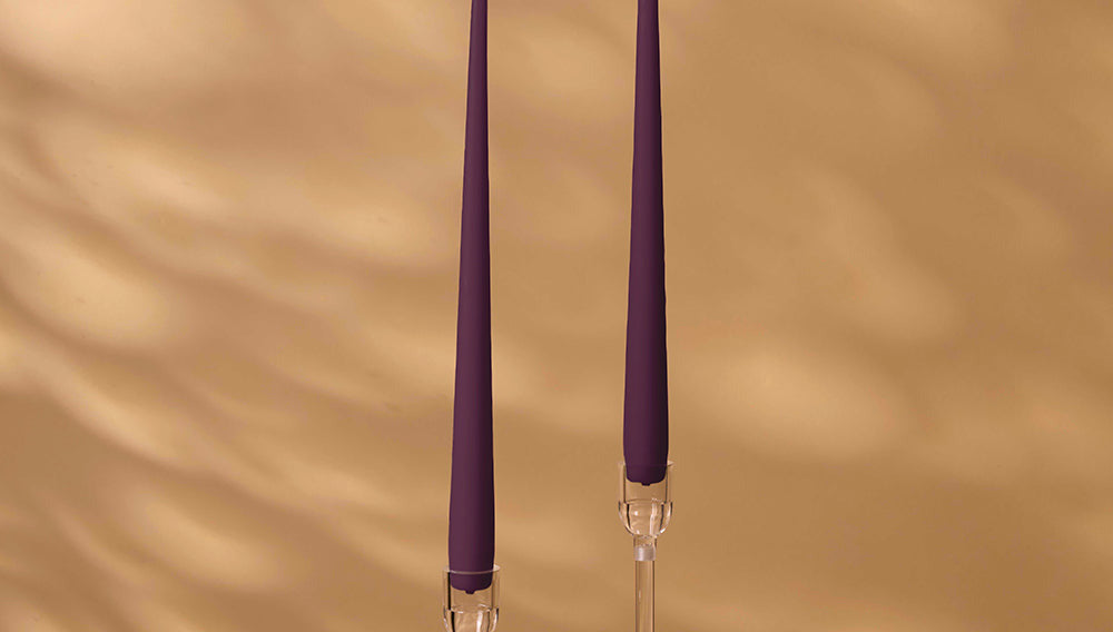 Two purple candles with clear holders on a beige background