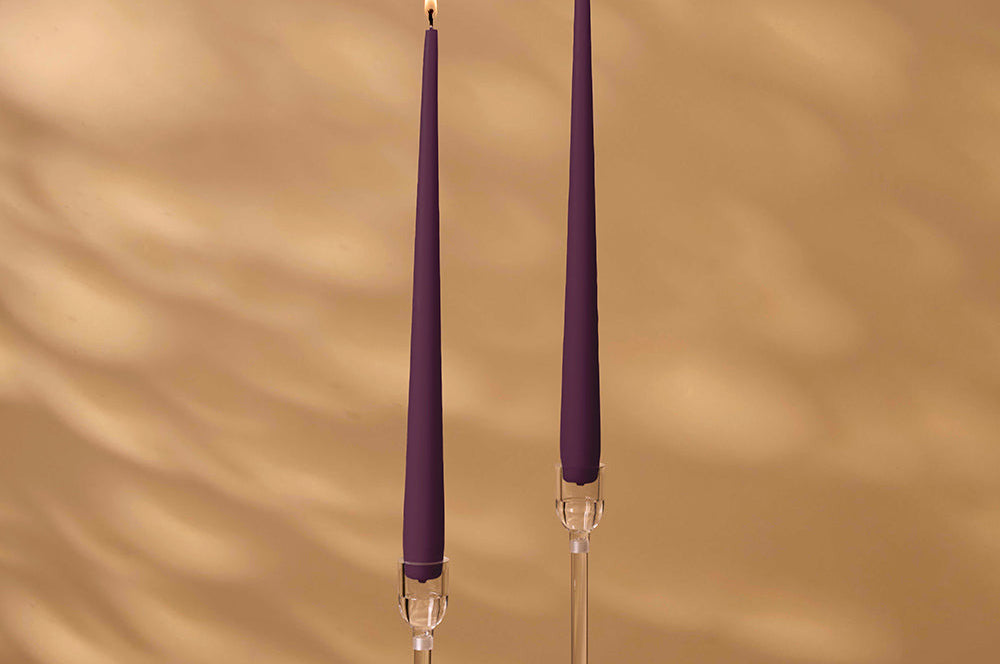 Two purple candles with clear holders on a beige background