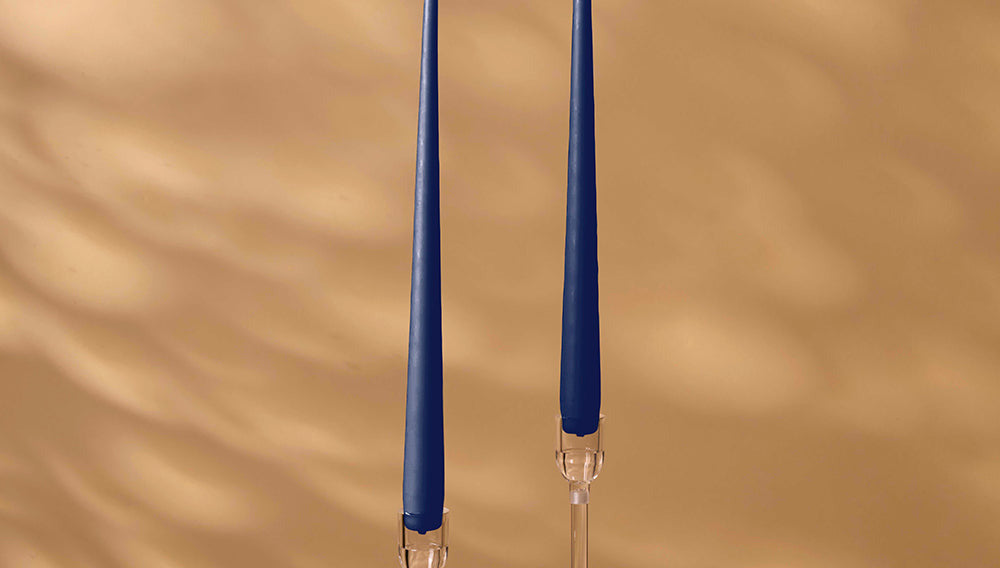 Two blue candles with clear holders on a beige background