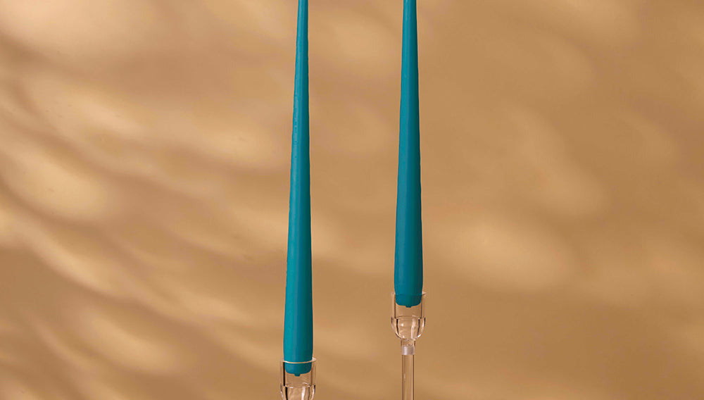 Two blue candles with clear holders on a beige background