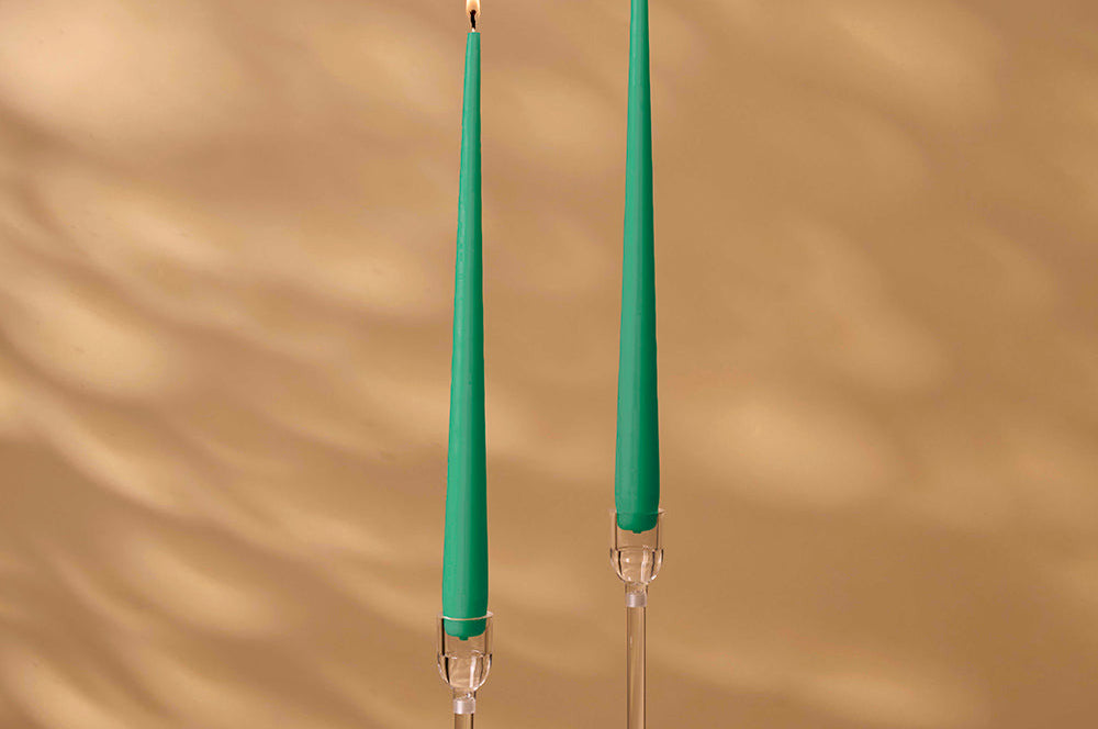 Two green candles with clear holders on a beige background