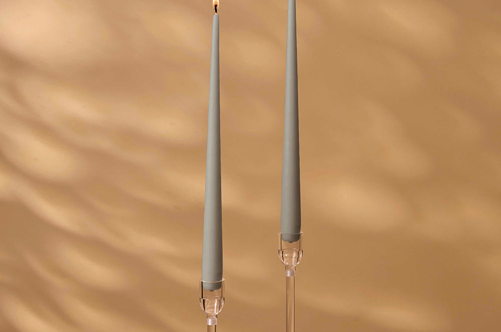 Two gray candles with clear holders on a brown background