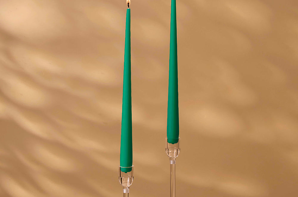 Two green candles with clear holders on a beige background