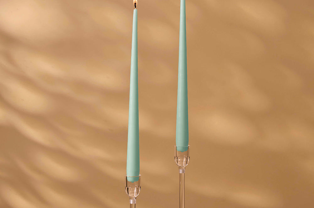 Two teal candles with clear holders on a brown background