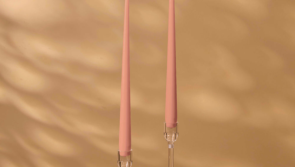 Two pink candles with clear holders on a beige background