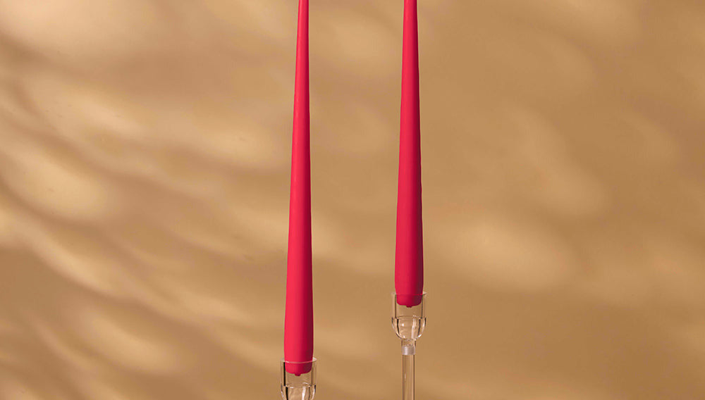 Two pink candles with clear holders on a beige background