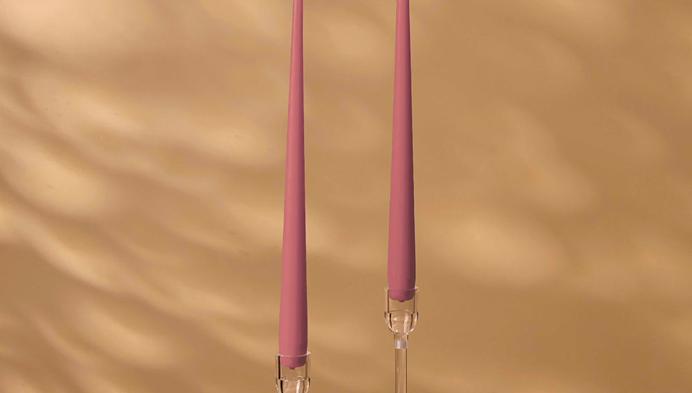 Two pink candles with clear holders on a beige background
