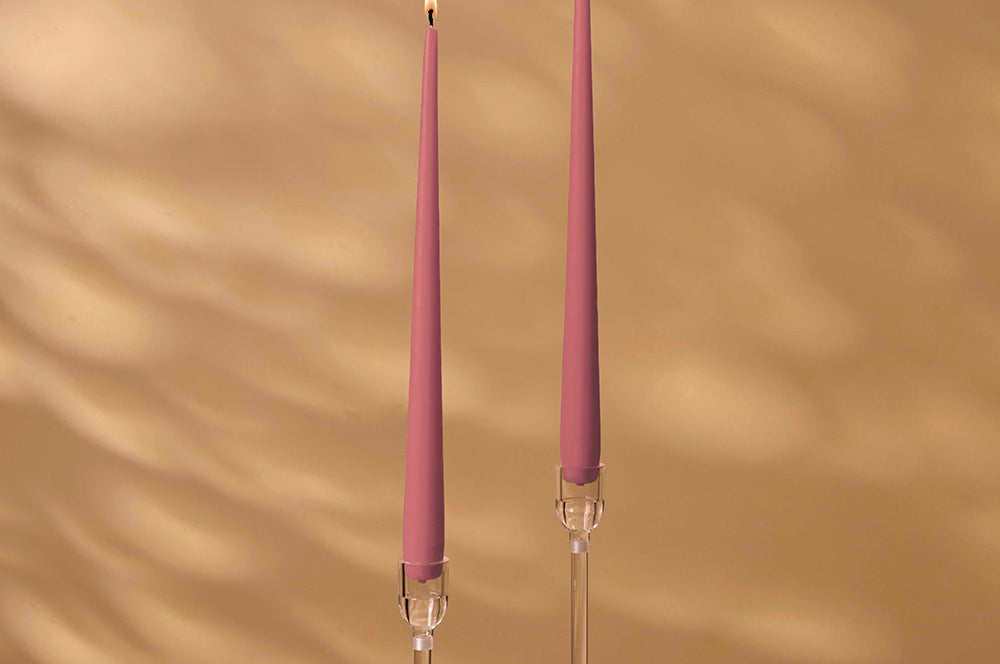 Two pink candles with clear holders on a beige background