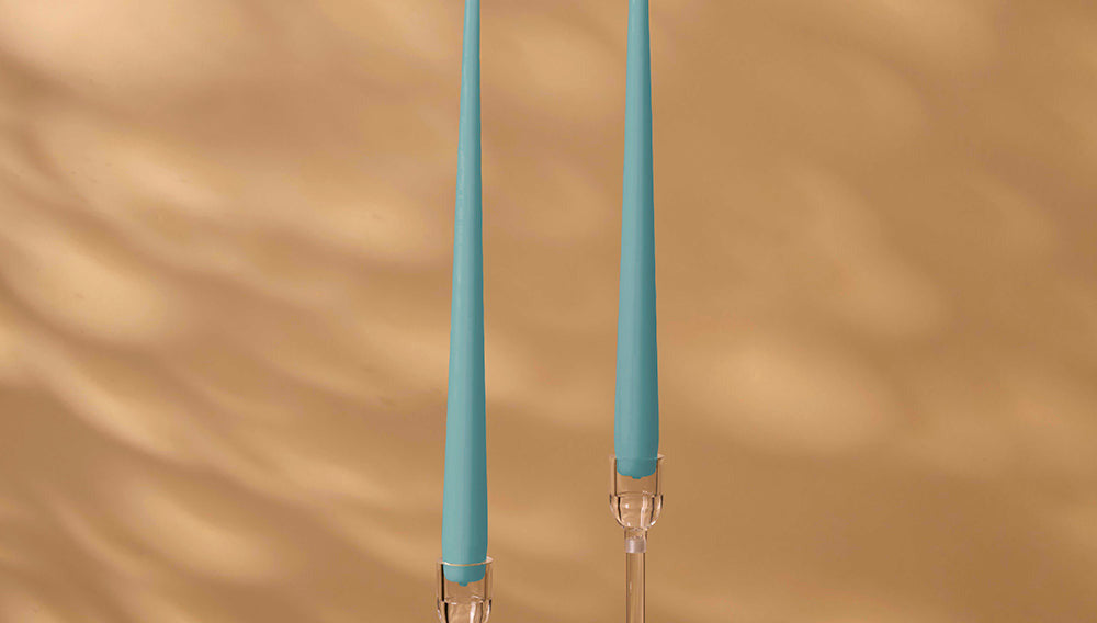 Two blue candles with clear holders on a brown background
