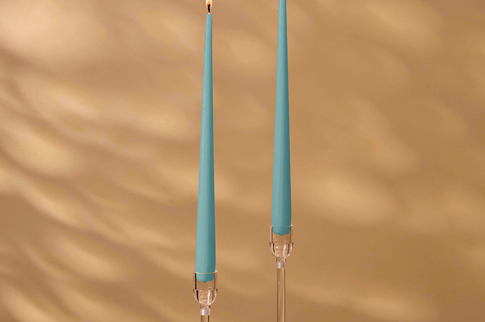 Two blue candles with clear holders on a brown background