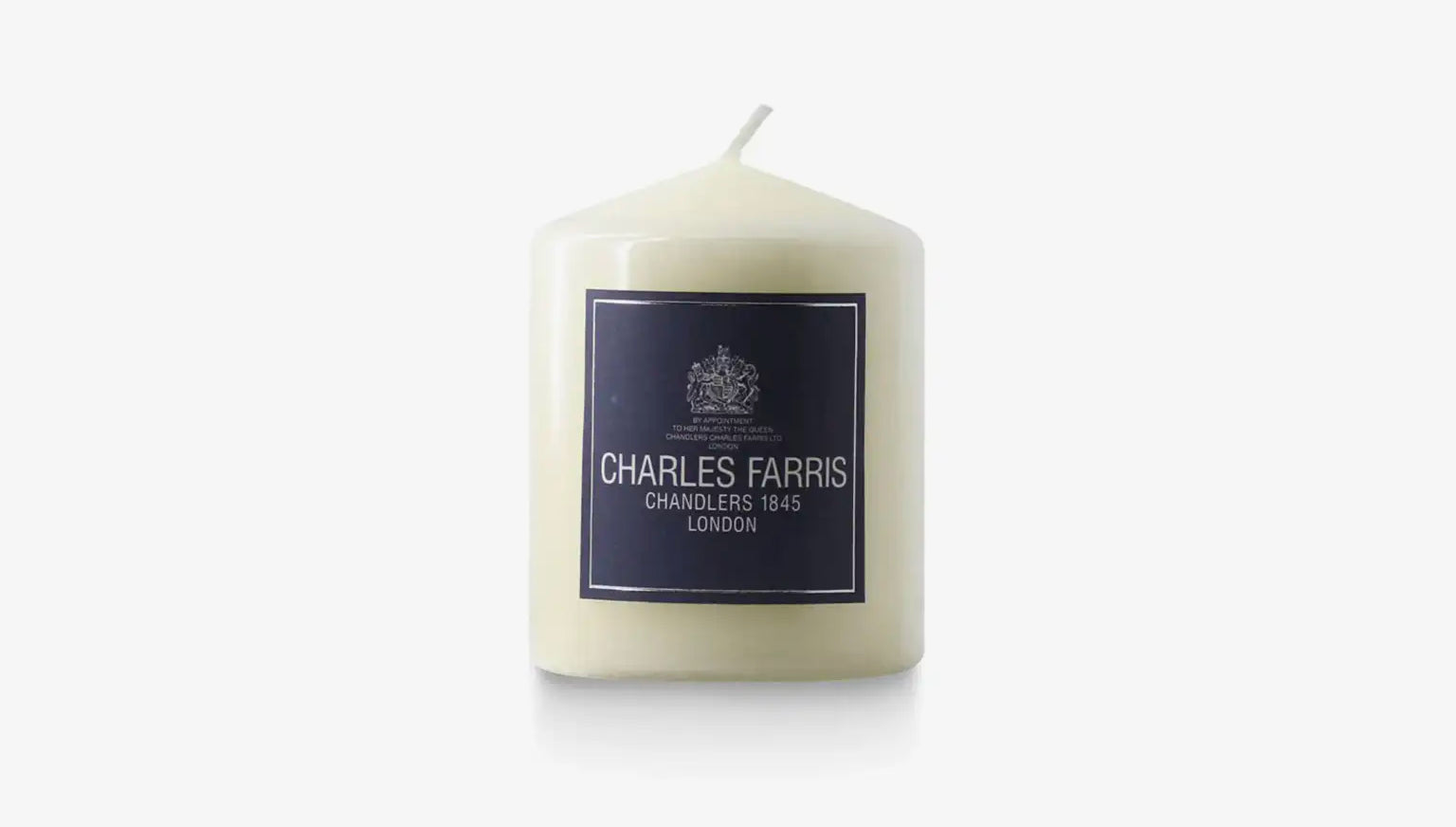 White candle with a dark label featuring 'Charles Farris' on a white background