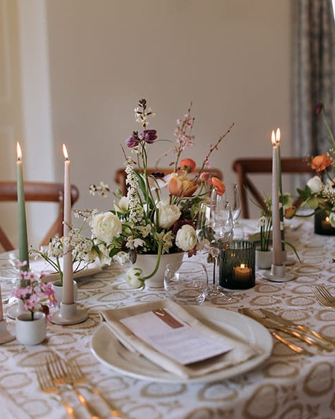 Elegant table setting with floral centerpieces, candles, and place settings.