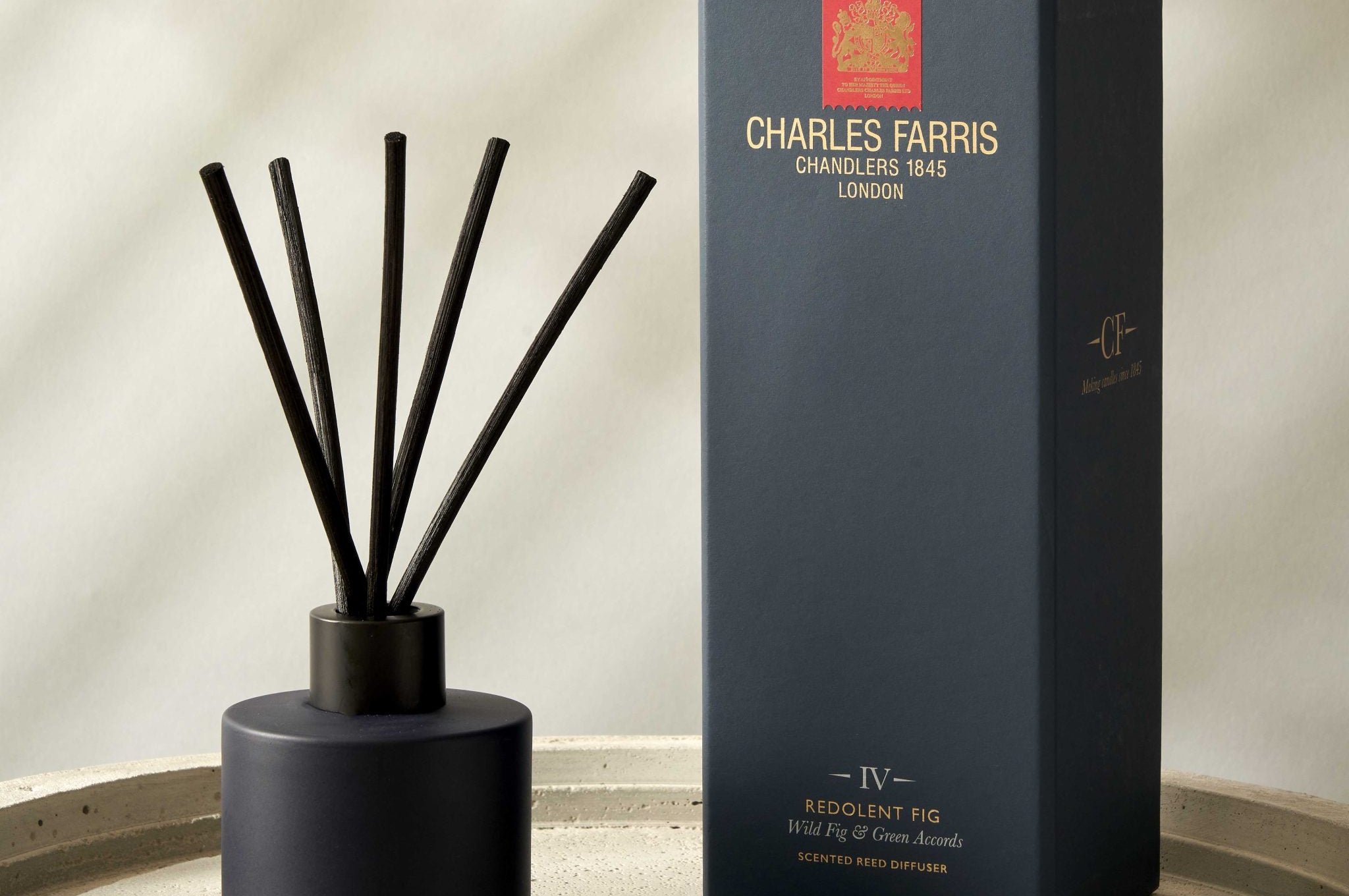 Reed diffuser with sticks and its packaging on a beige surface