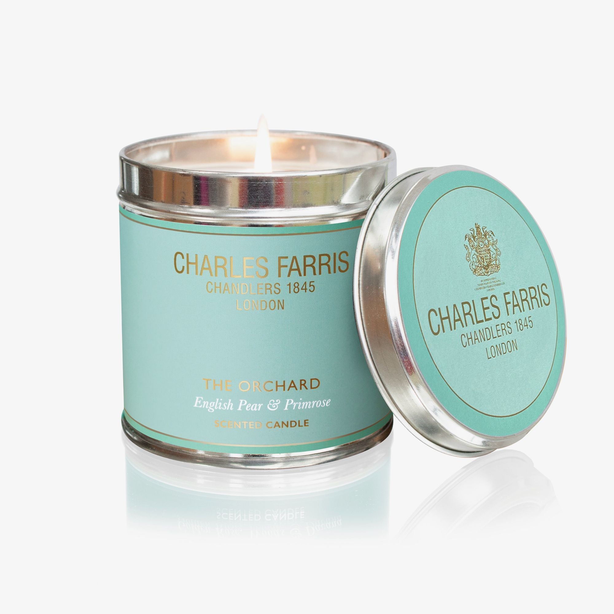 Charles Farris candle with teal label and silver lid on a white background