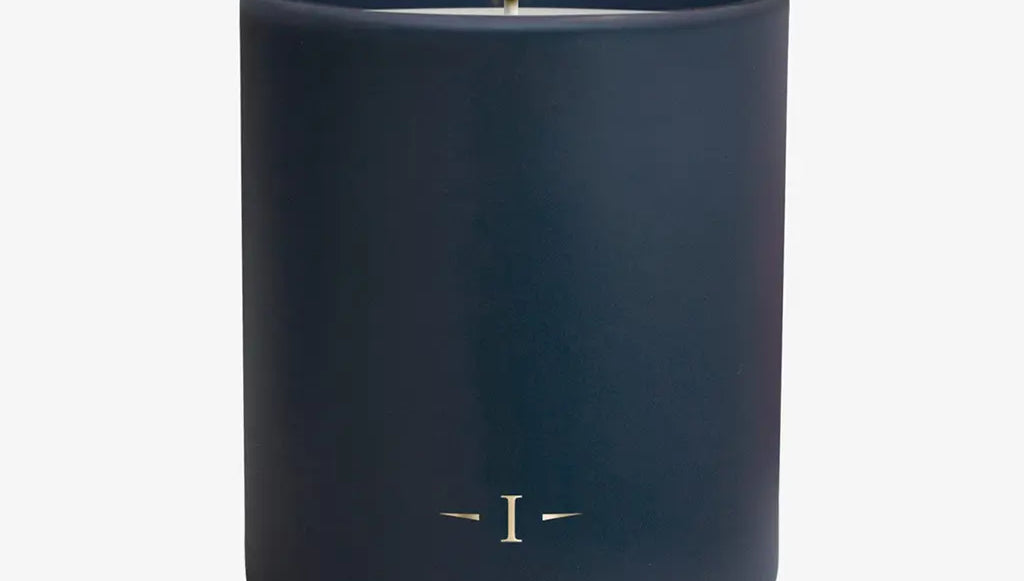 Navy blue candle with a lit wick on a white background