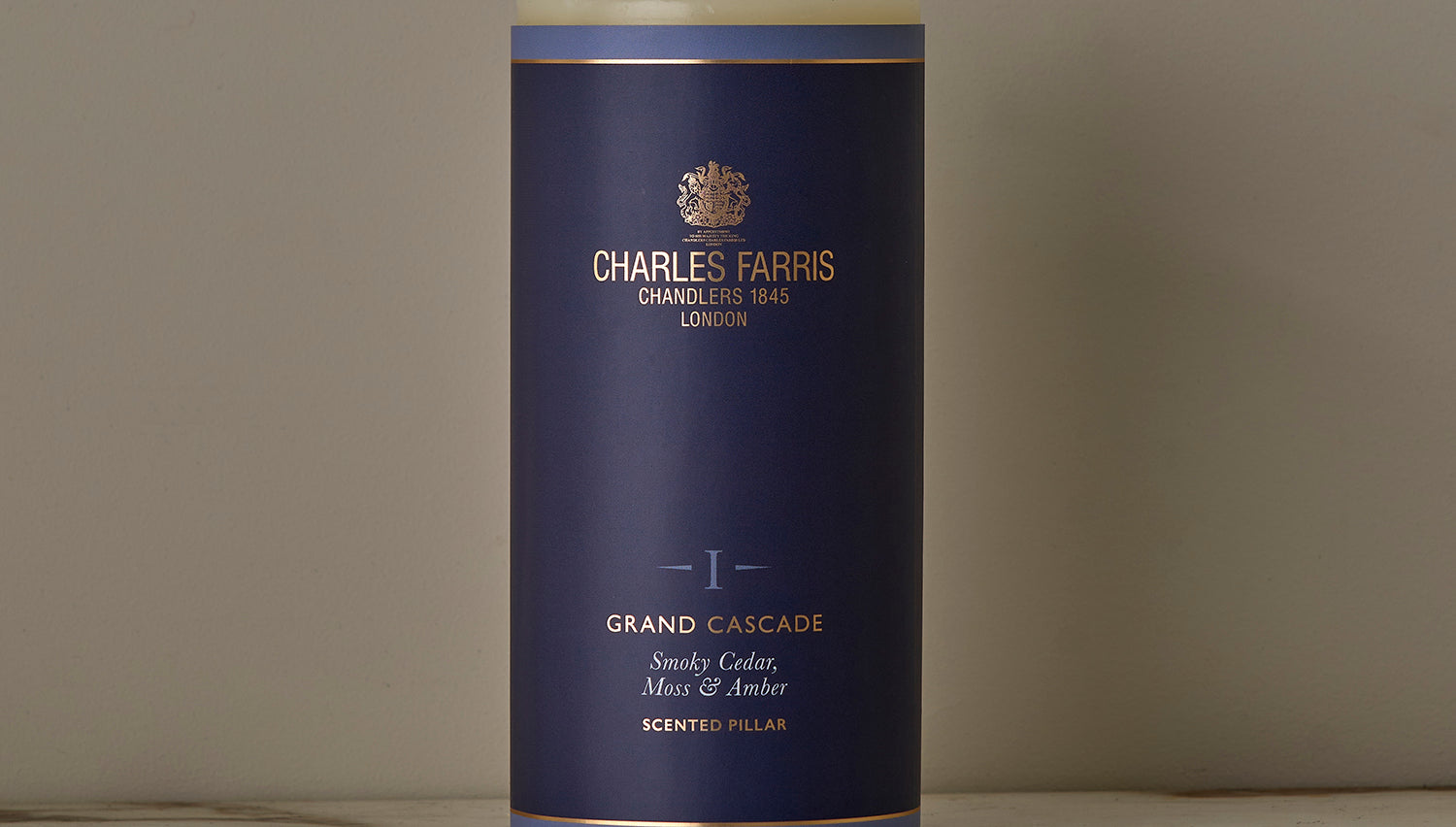 A Grand Cascade Scented Pillar Candle on a marble surface.