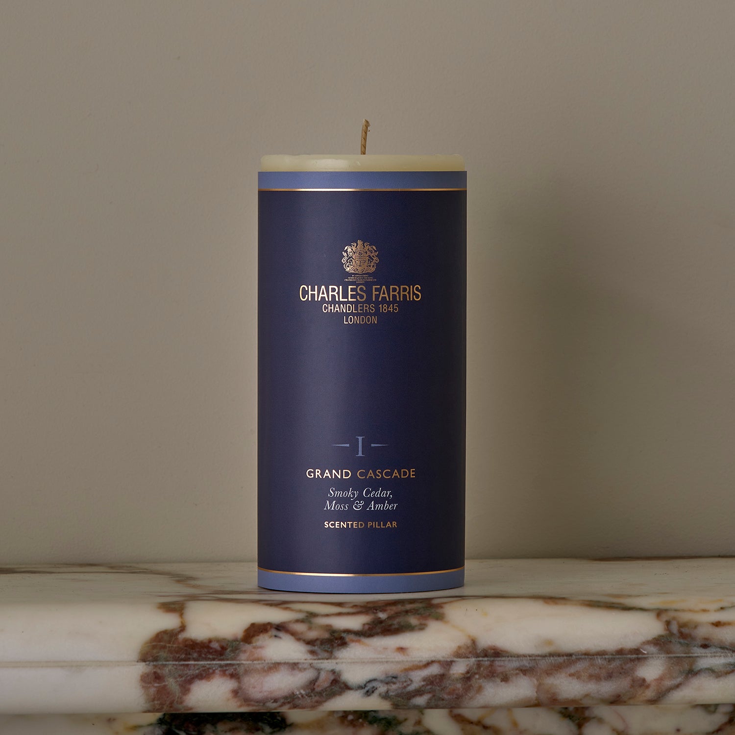 A Grand Cascade Scented Pillar Candle on a marble surface.