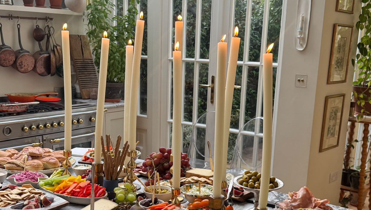 Dining room with a table set for a meal featuring dining candles, fruits, vegetables, and bread.