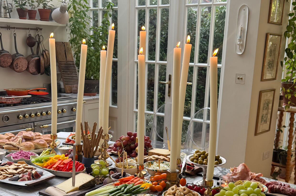 Dining room with a table set for a meal featuring dining candles, fruits, vegetables, and bread.