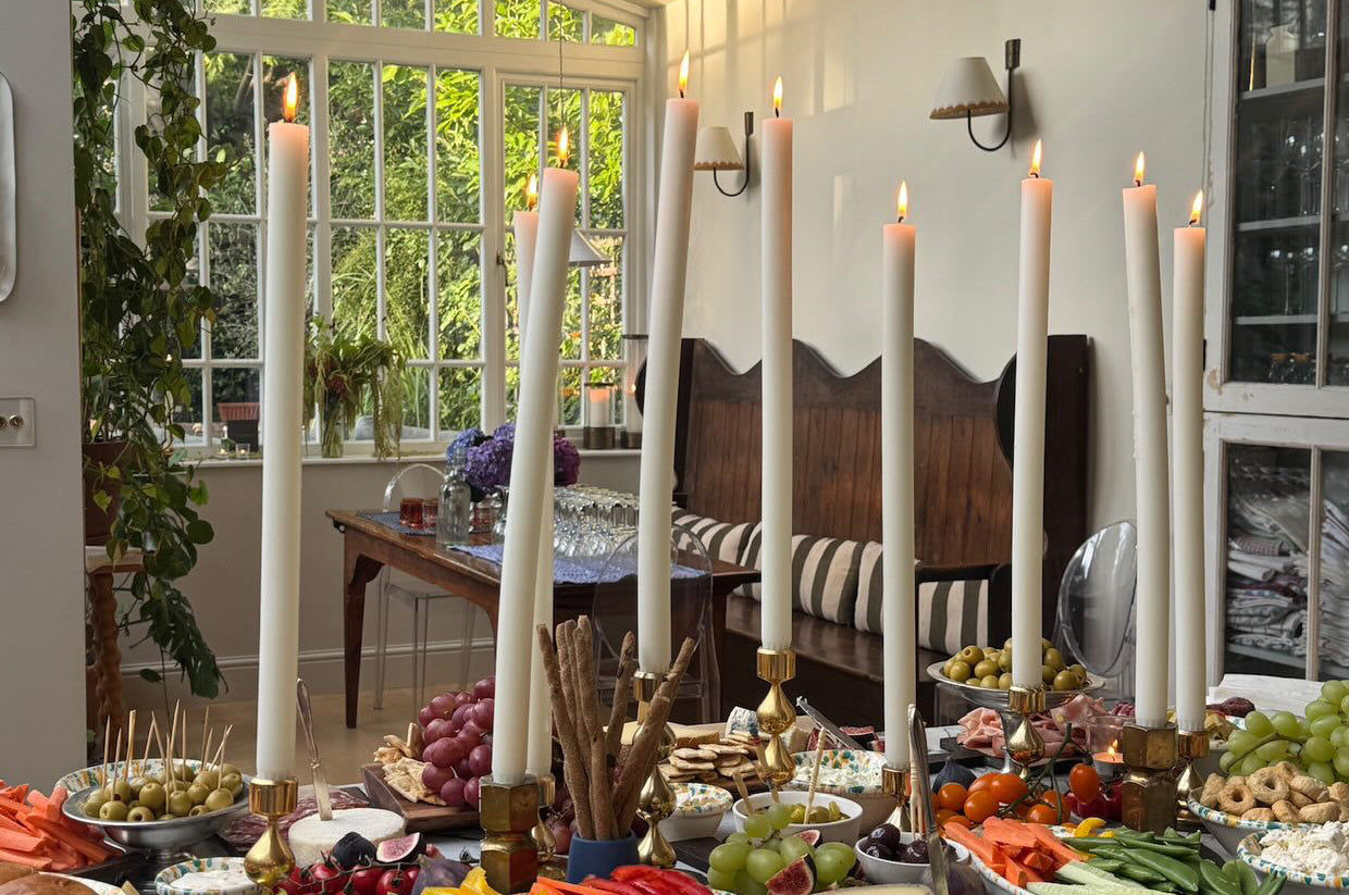 Dining room with a table set for a meal featuring dining candles, fruits, vegetables, and bread.
