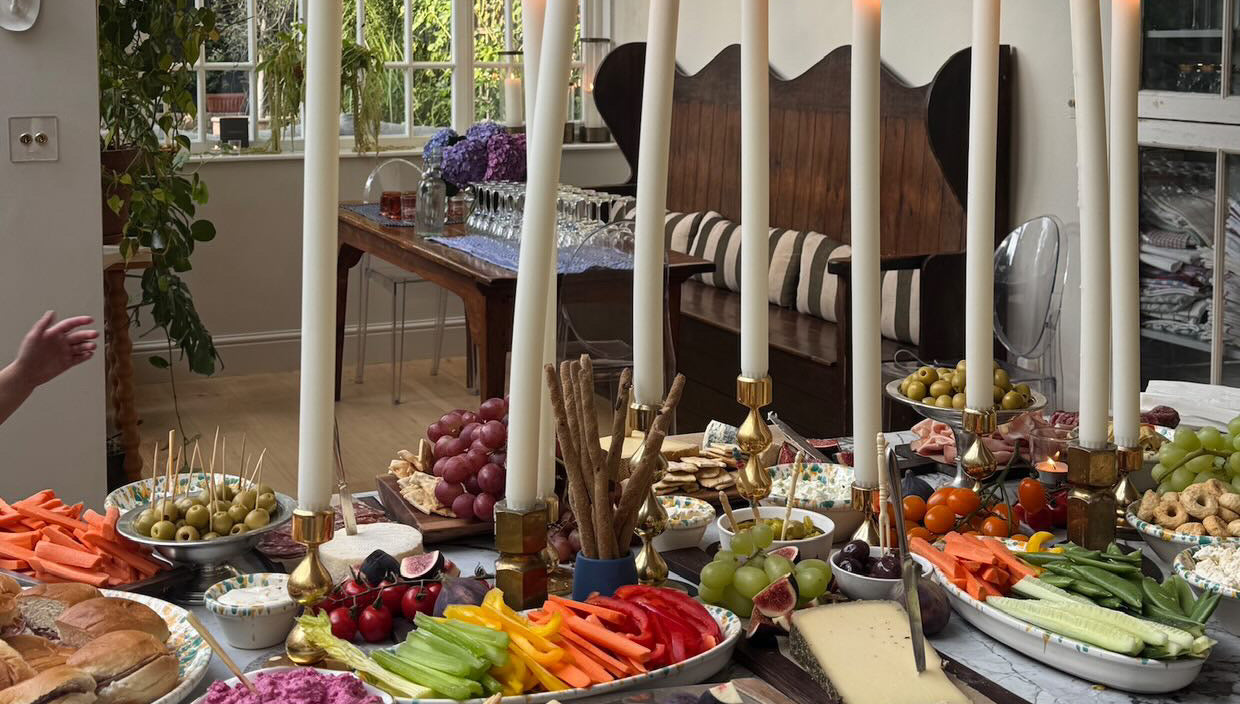 Dining room with a table set for a meal featuring dining candles, fruits, vegetables, and bread.