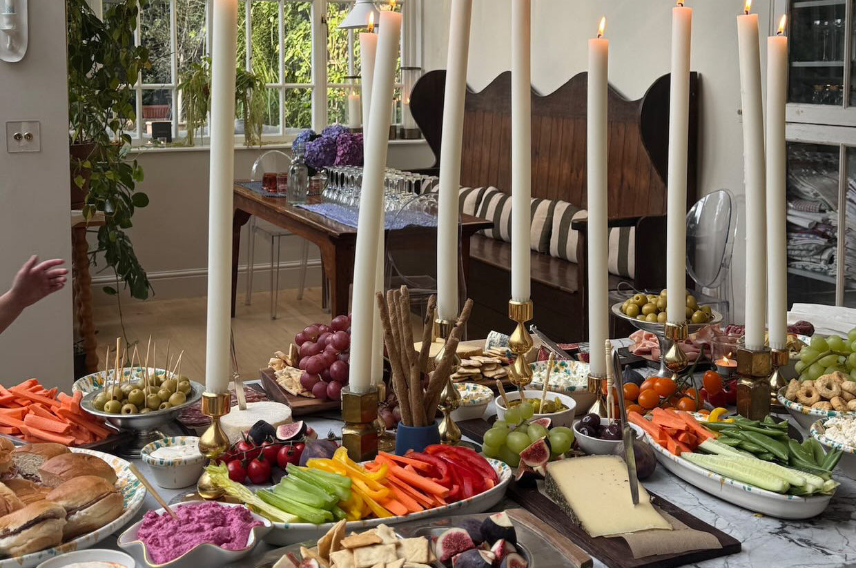 Dining room with a table set for a meal featuring dining candles, fruits, vegetables, and bread.