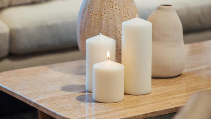 Decorative vases and candles on a wooden coffee table with a blurred sofa in the background