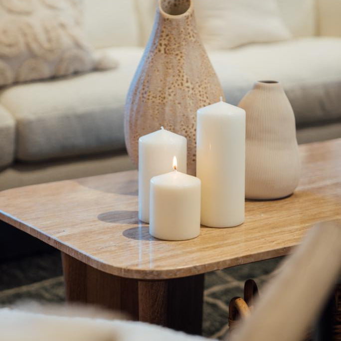 Decorative vases and candles on a wooden coffee table with a blurred sofa in the background