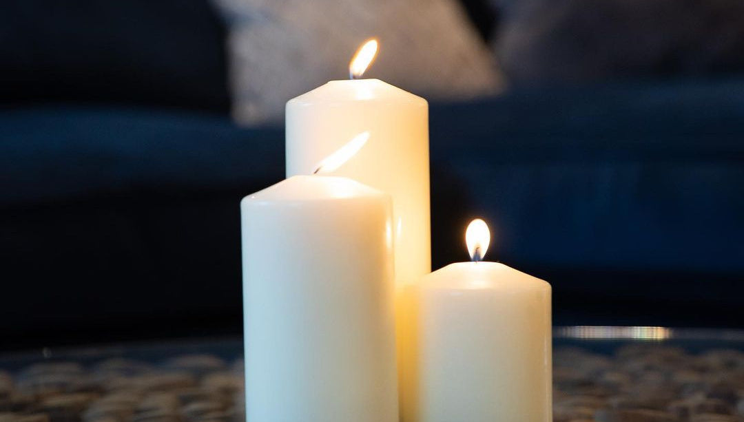 Three lit candles on a stone surface with a blurred indoor background