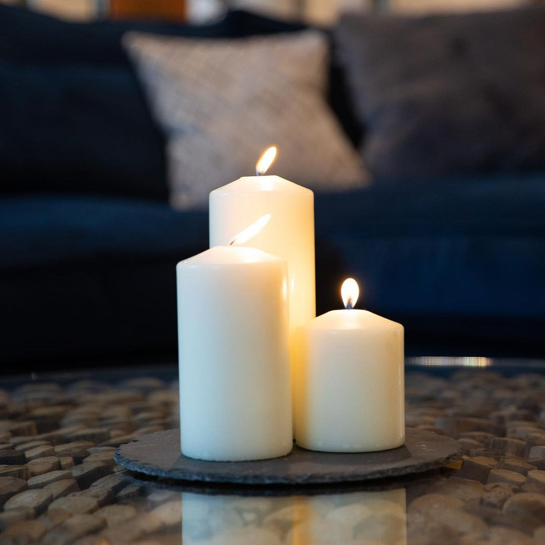 Three lit candles on a stone surface with a blurred indoor background