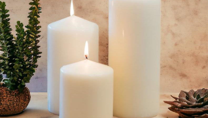 Three white candles on a wooden surface with a textured wall background