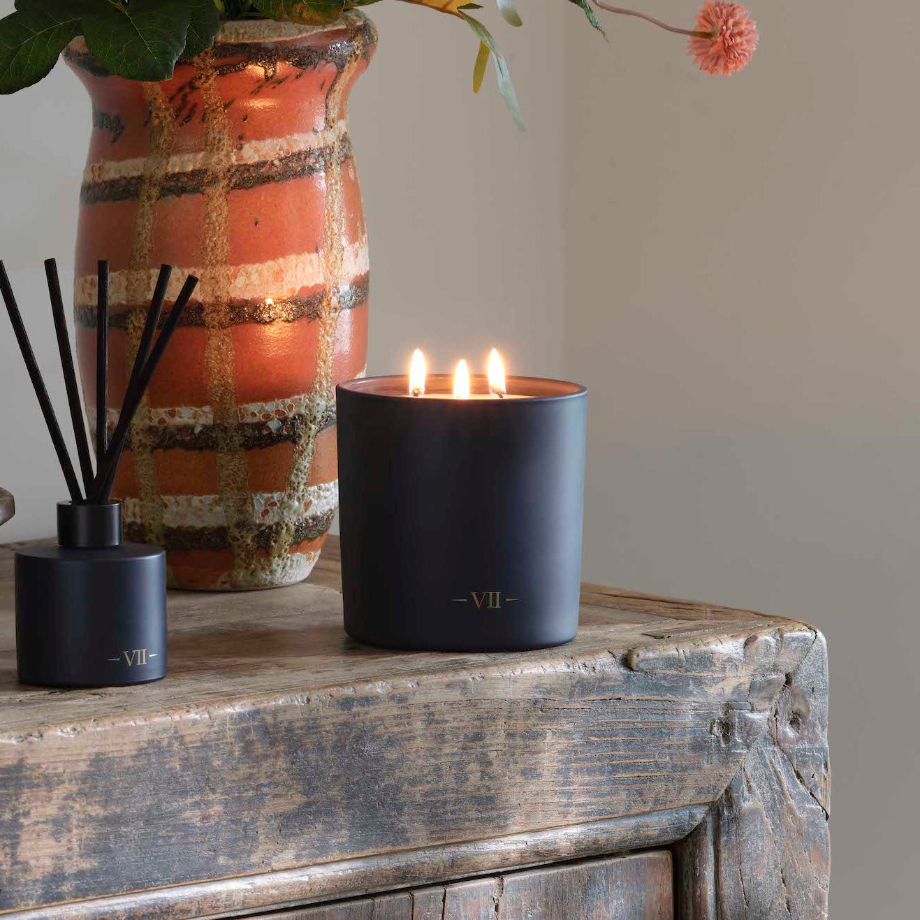 Candle with reed diffuser on a wooden surface with a neutral background