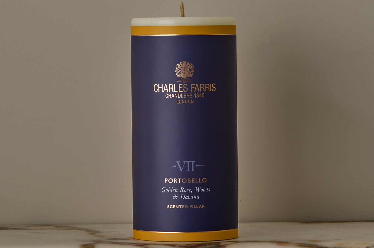 A Portobello Scented Pillar Candle on a marble surface.