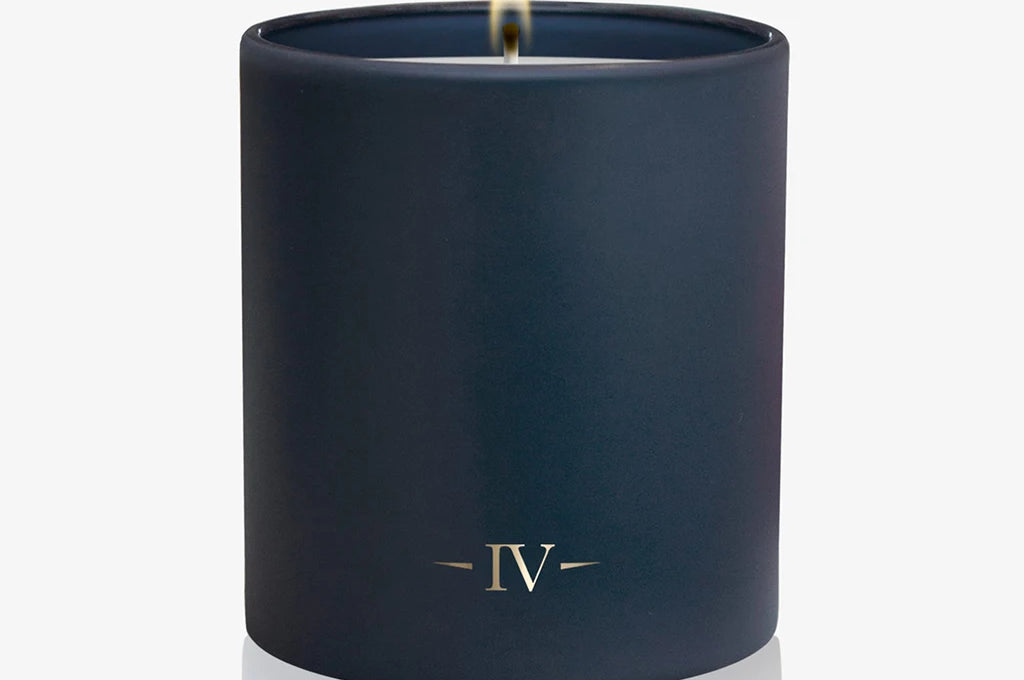 Navy blue candle with a lit wick on a white background