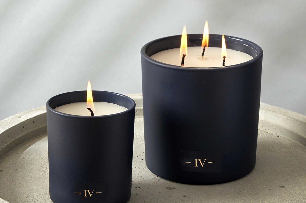 Two candles labeled 'IV' on a gray surface with a neutral background