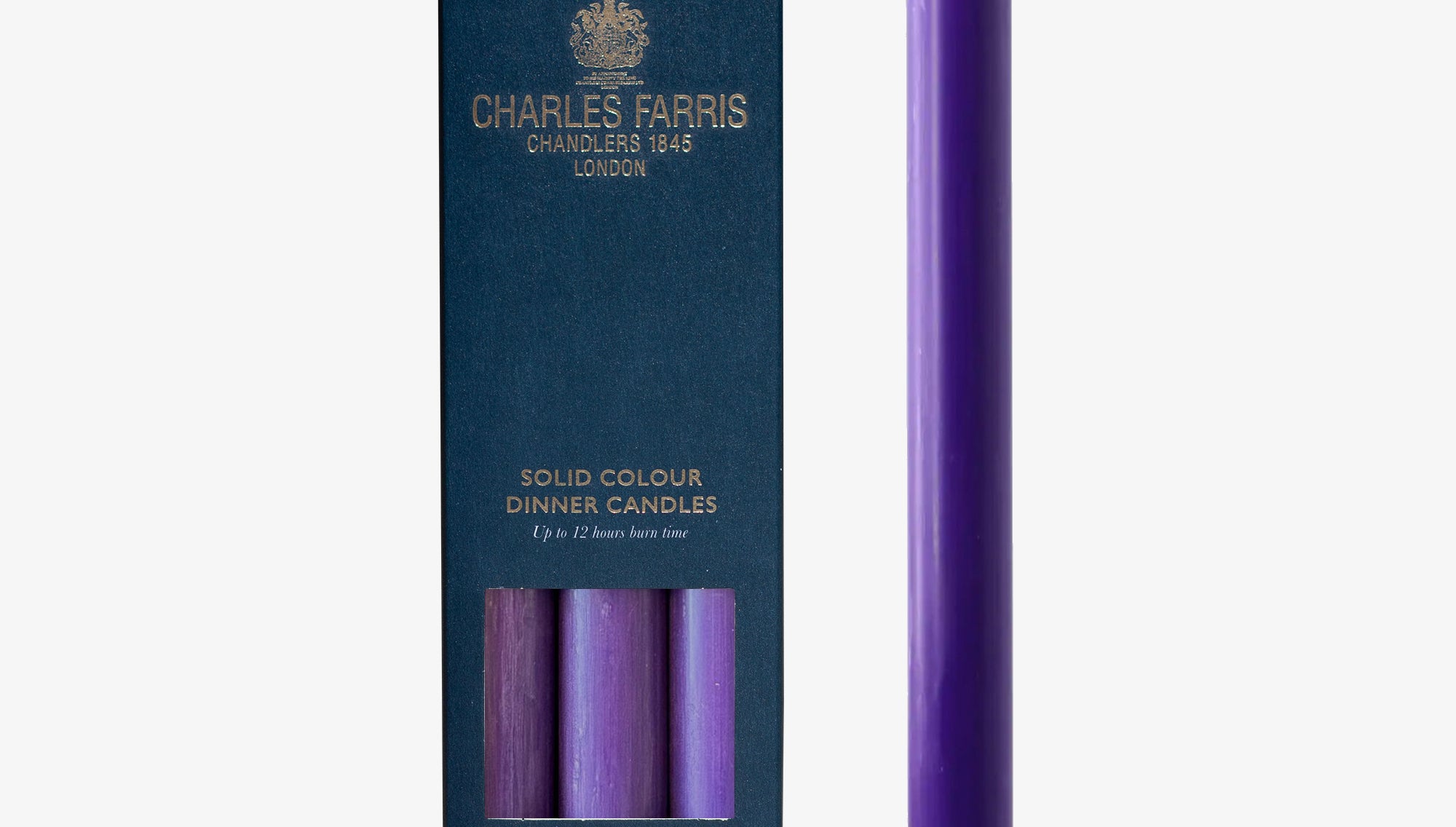 Purple candle next to its packaging with 'Charles Farris' branding on a white background
