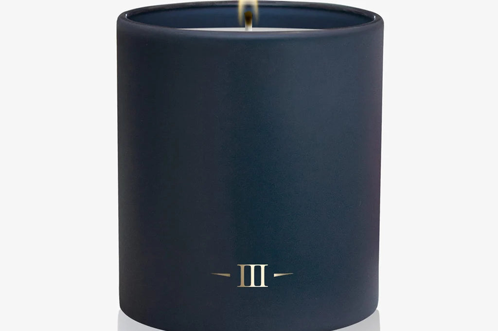 Navy blue candle with a flame on a white background