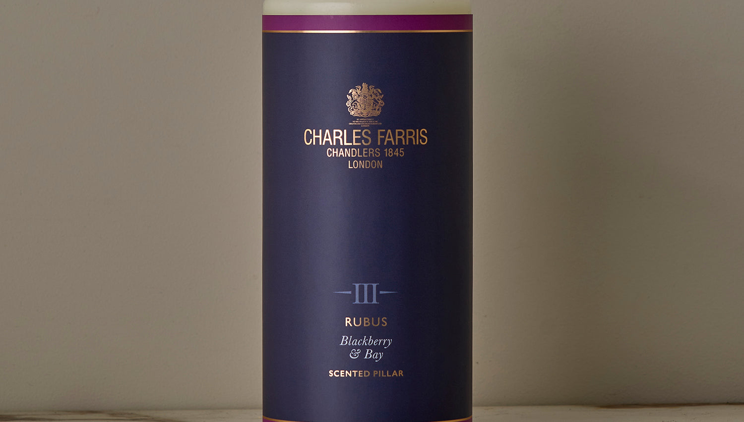 A Rubus Scented Pillar Candle on a marble surface.
