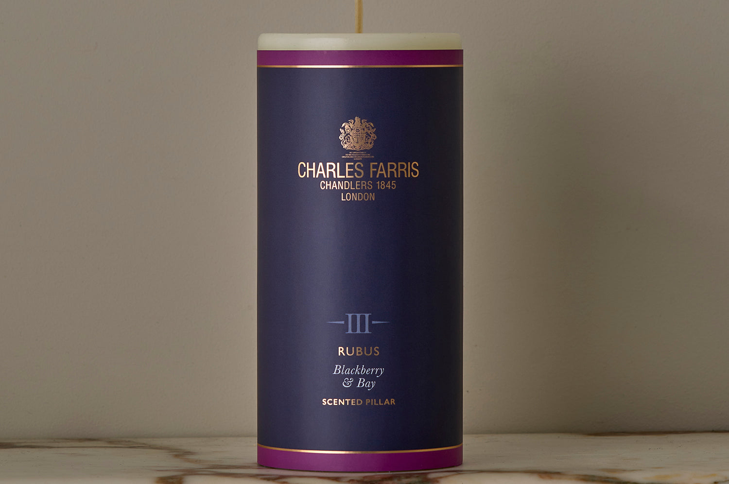 A Rubus Scented Pillar Candle on a marble surface.