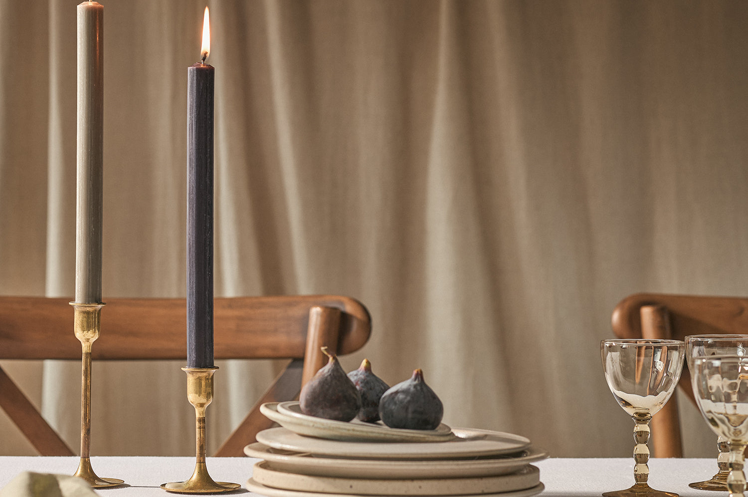 Two lit dinner candles on a table with plates