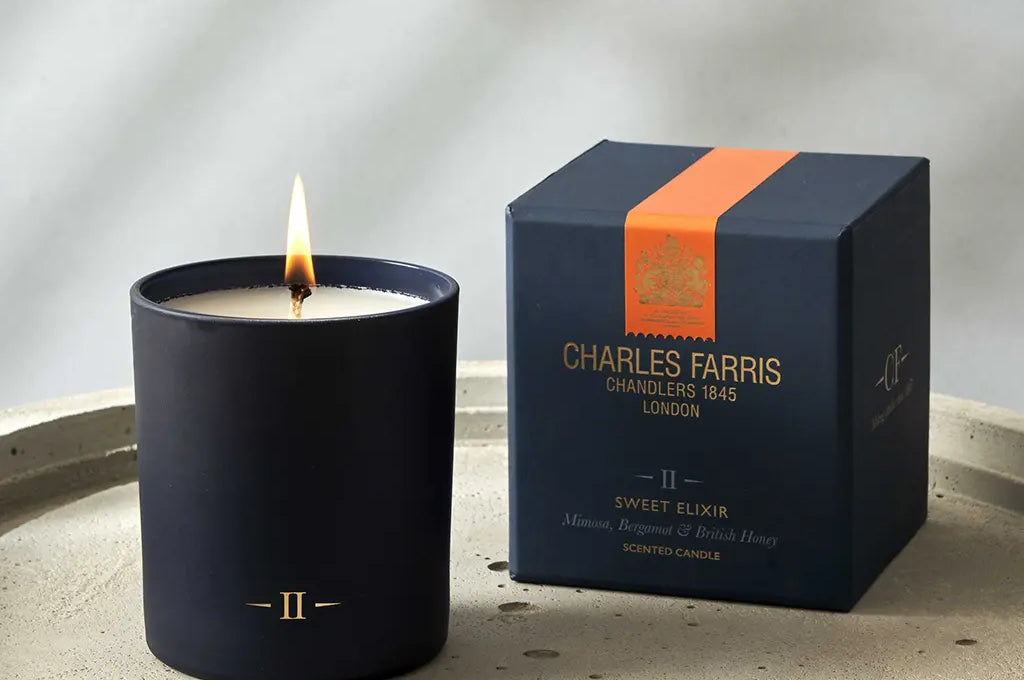 Candle and its packaging on a textured surface with a neutral background