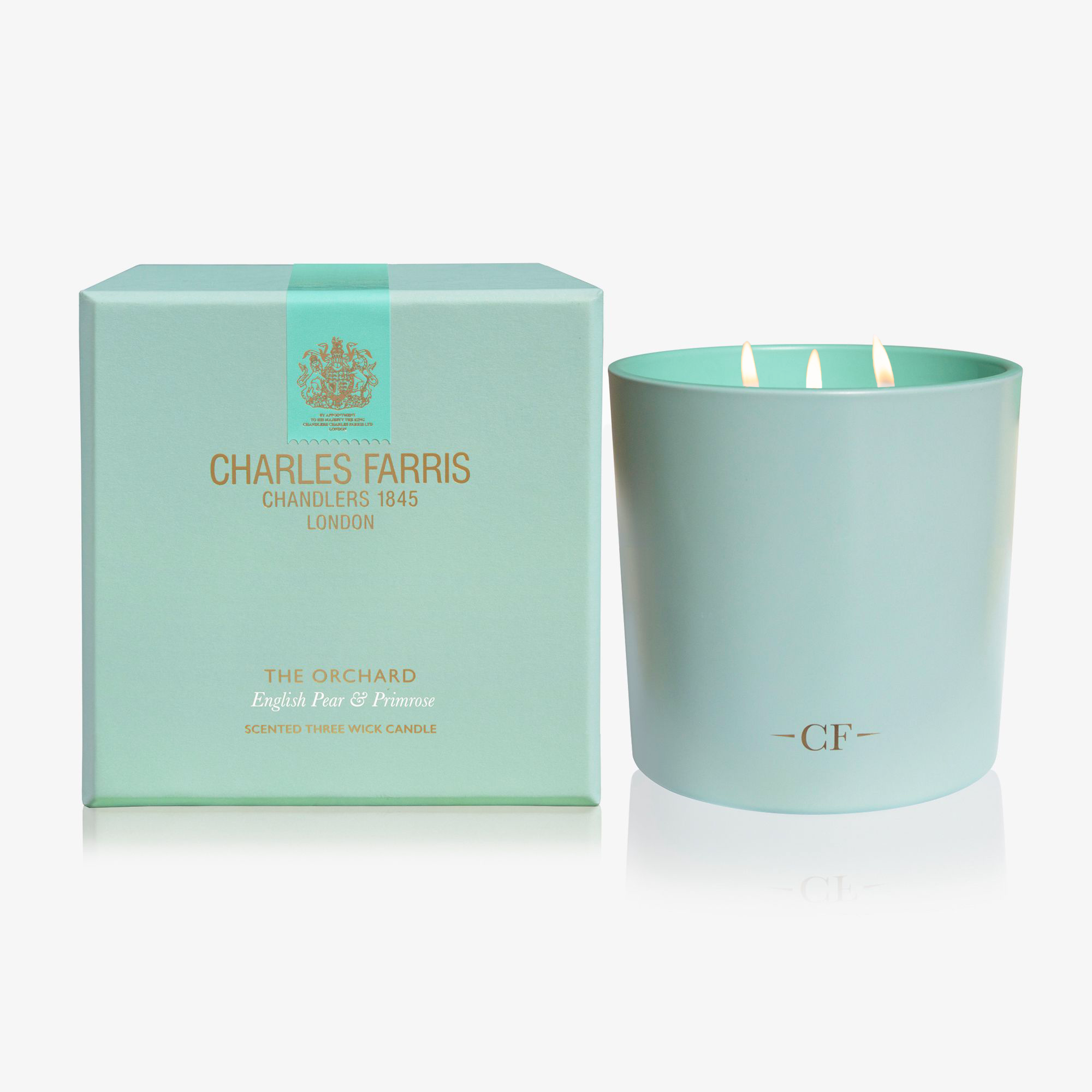 Mint green candle with 'Charles Farris' branding next to its packaging on a white background