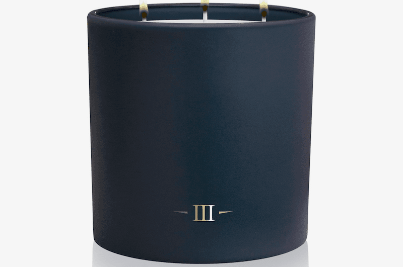 Navy blue candle with three wicks on a white background