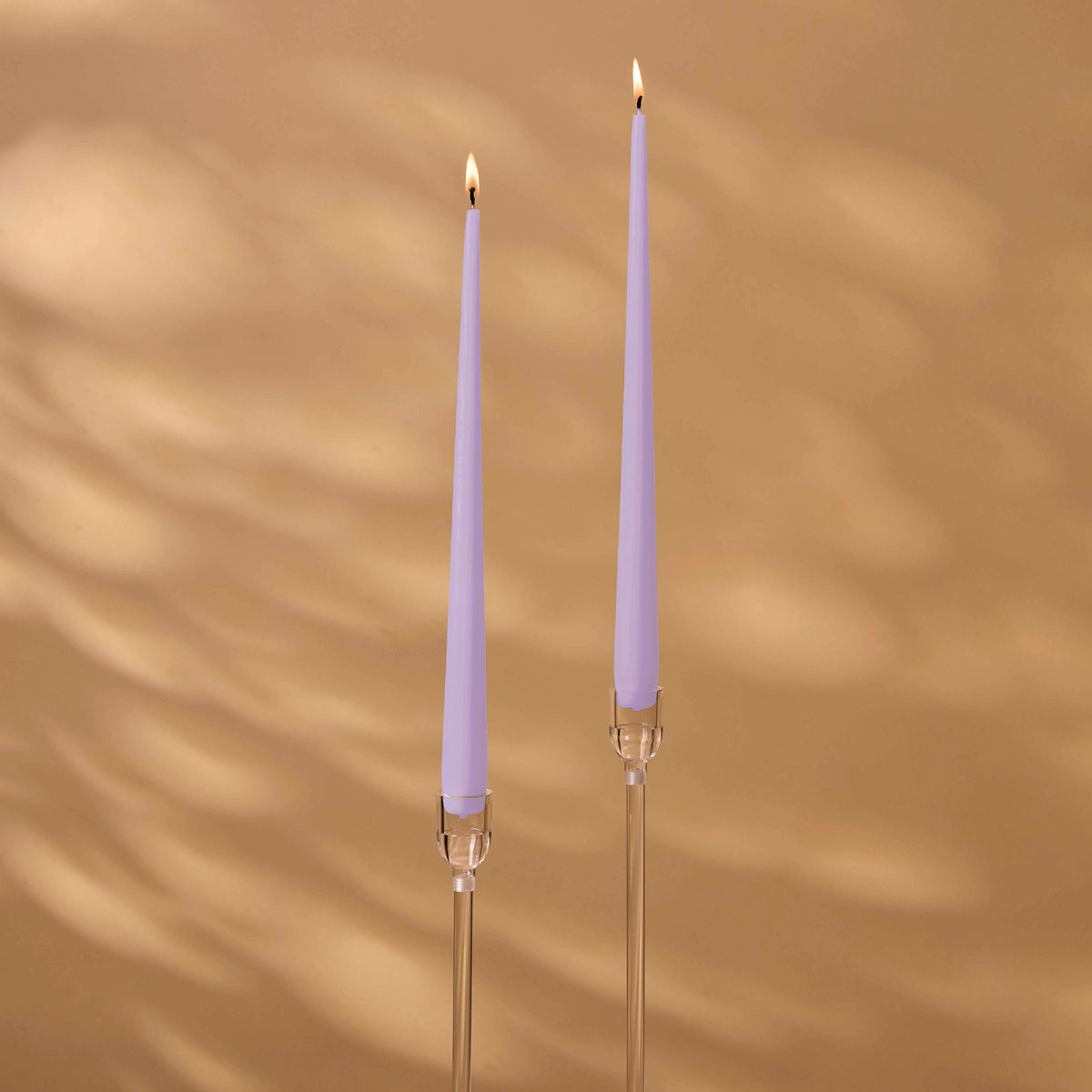 Charles Farris lilac tapered dinner candles, a lit pair in tall clear holders, made in England