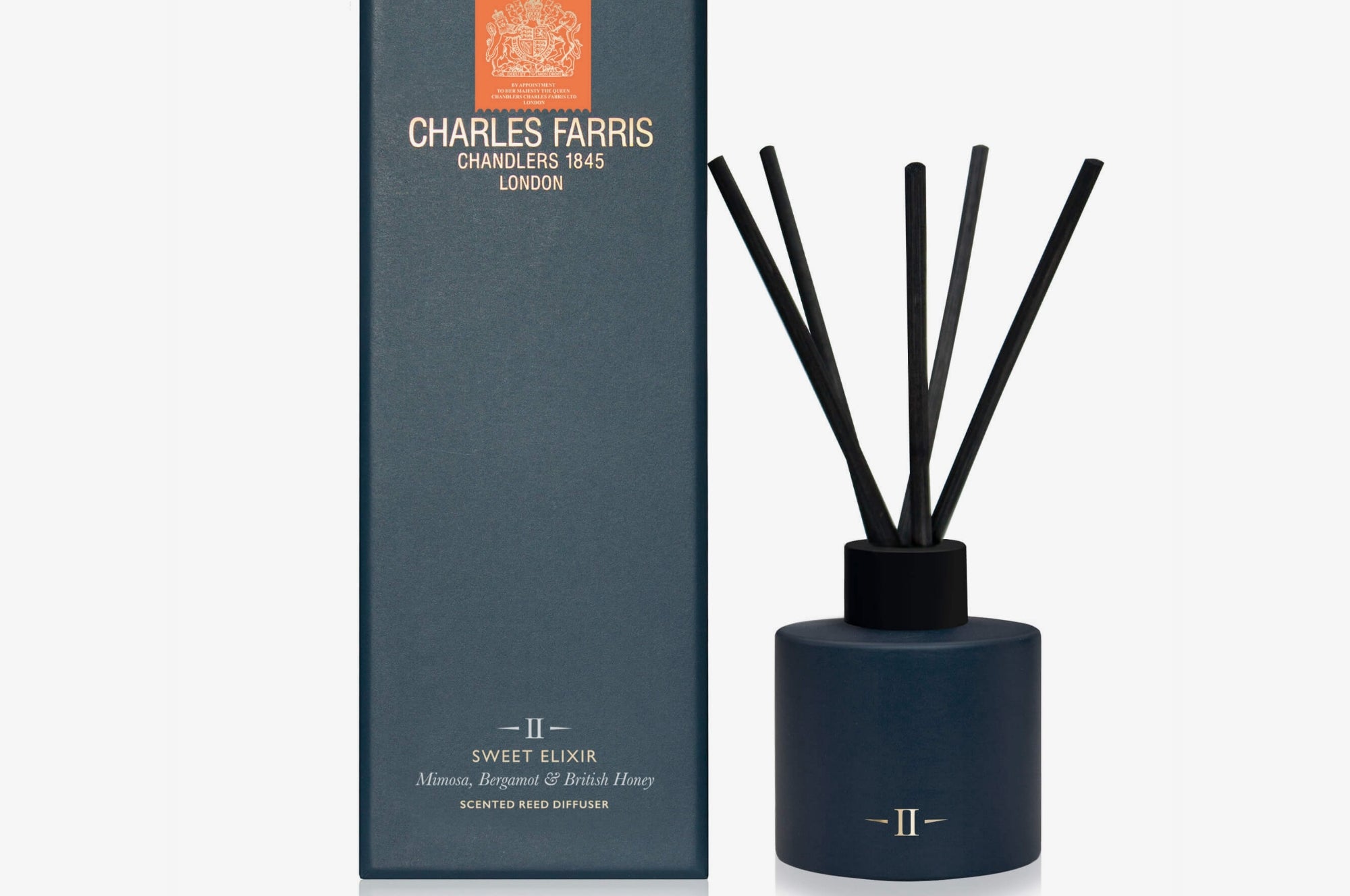 Dark blue diffuser bottle with black sticks and packaging on a white background