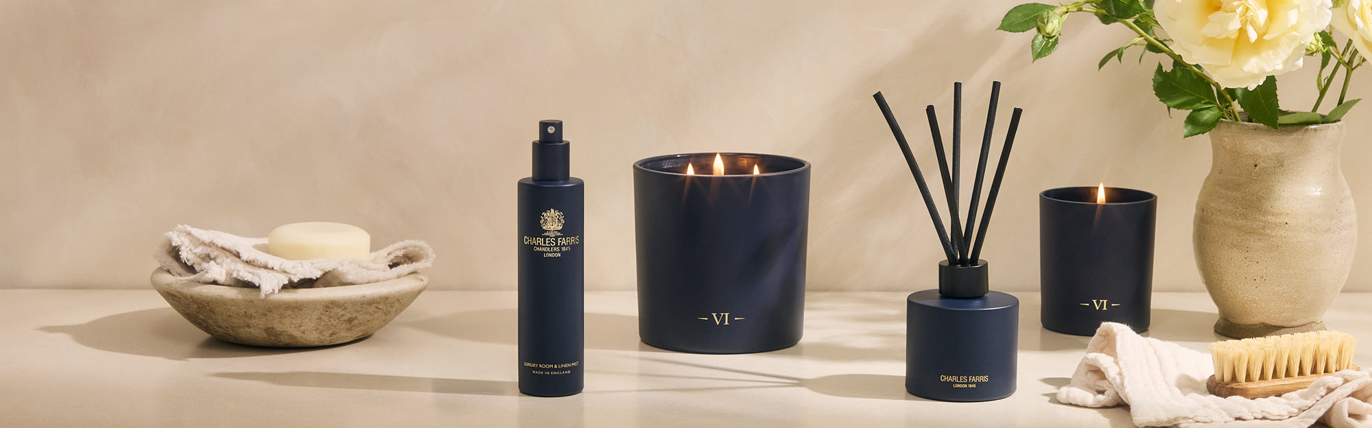 Charles Farris Garden of Eden home fragrance collection - luxury room and linen mist, three-wick candle, reed diffuser and candle - styled with roses on a neutral backdrop collection strip