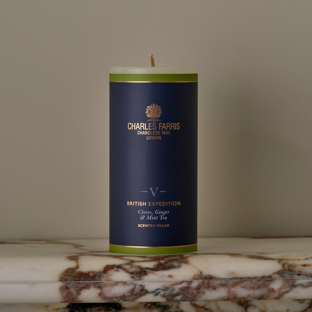 Candle with a blue label featuring 'Charles Farris' branding on a marble surface.