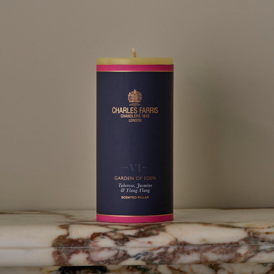 Candle with a dark blue label featuring 'Charles Farris' branding on a marble surface.